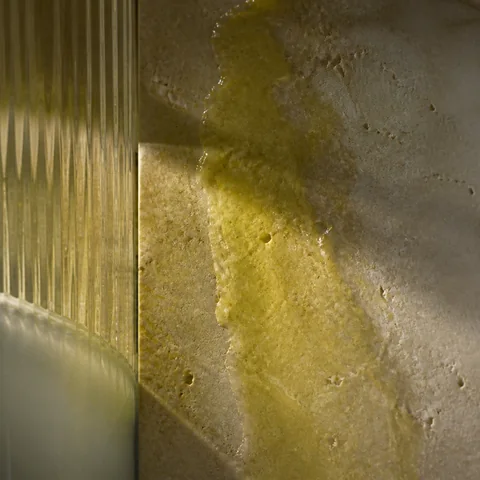 A thin olive-oil sheen catching green-gold light on fluted glass.